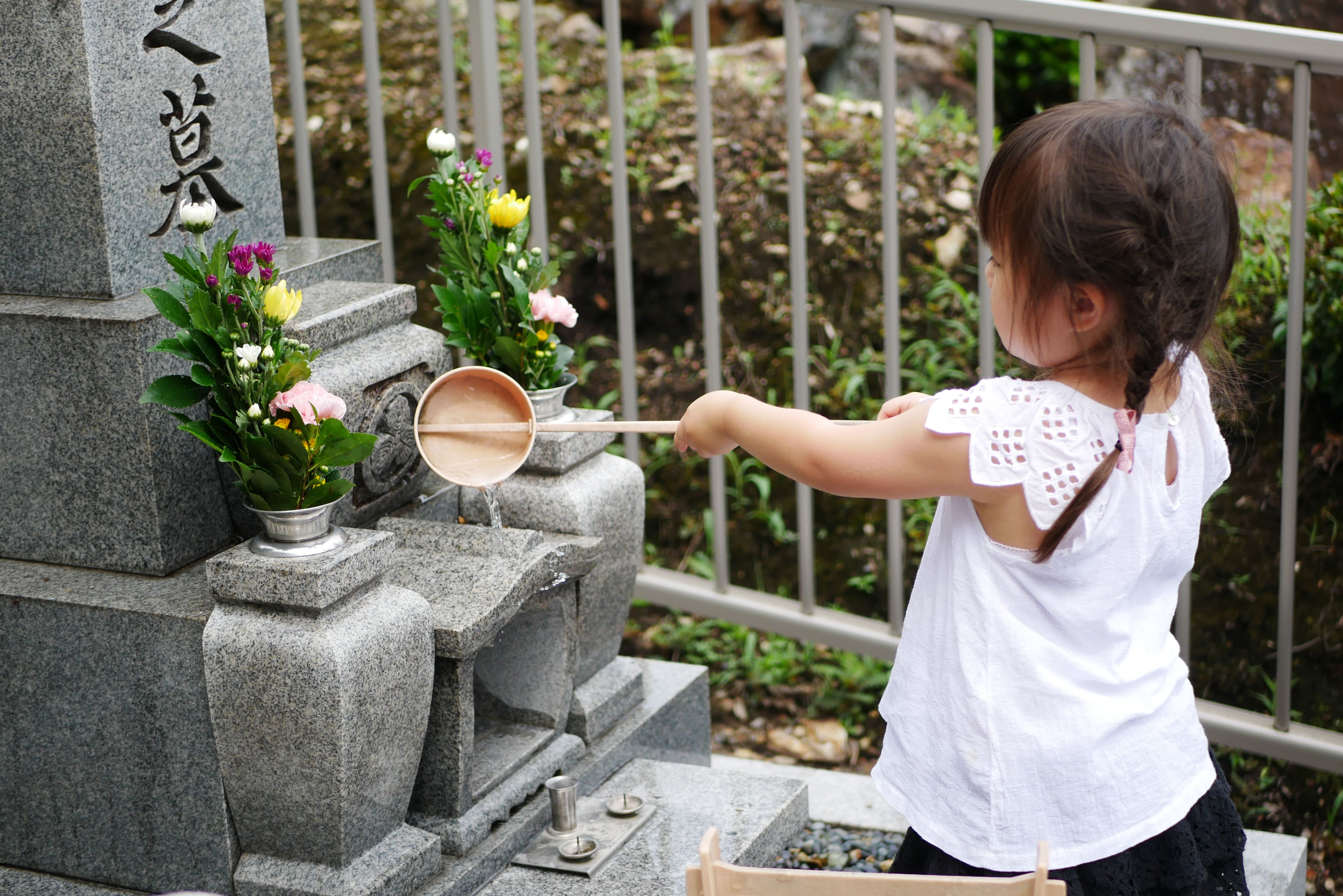 お墓参りで手を合わせる家族