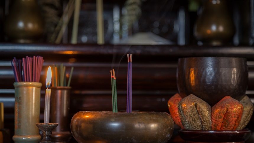 火の灯るろうそくと線香が供えられている仏壇